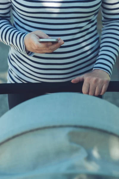 Anya mobiltelefon használata közben nyomja baby babakocsi — Stock Fotó