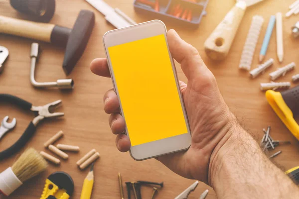 Handyman holding smart phone with blank screen in hand — Stock Photo, Image