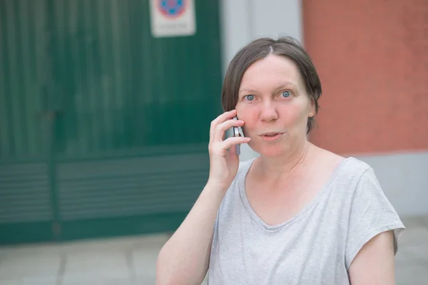 Verrast vrouw praten op mobiele telefoon uit op de straat — Stockfoto