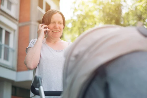 Счастливая мать разговаривает по мобильному телефону — стоковое фото