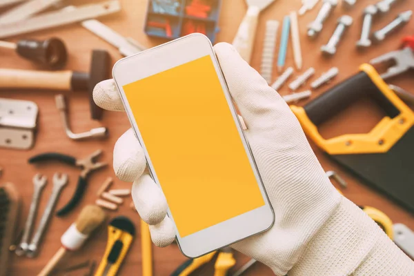 Handyman smart phone app, repairman holding mobile phone in hand