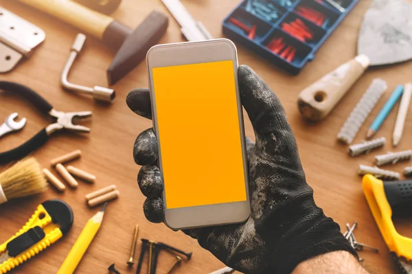 Handyman smart phone app, repairman holding mobile phone in hand — Stock Photo, Image