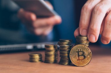 Bitcoin cryptocurrency tüccar, kripto para ile ticaret için modern teknoloji elektronik kullanan iş kişi paralar ön planda yığılmış ve işadamı arka planda defocussed