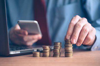 Smartphone ile kullanarak işadamı paralar ön planda yığılmış, seçici odak ile atış kadar yakın