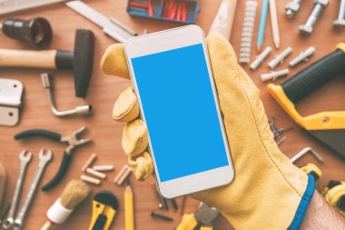 Tamirci akıllı telefon app araçları ile masa üzerinde. Telefon elinde tutan tamirci. Metin, en iyi görünüm için yer kopyalayın