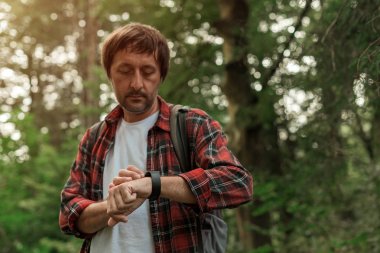 Ormanda yürürken erkek yürüyüşçünün elinde akıllı bir bakış açısı.