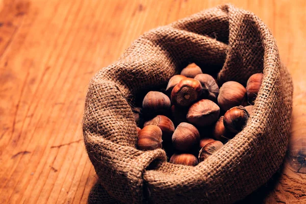 Hazelnut heap in burlap sack on wooden table — Stock Photo, Image