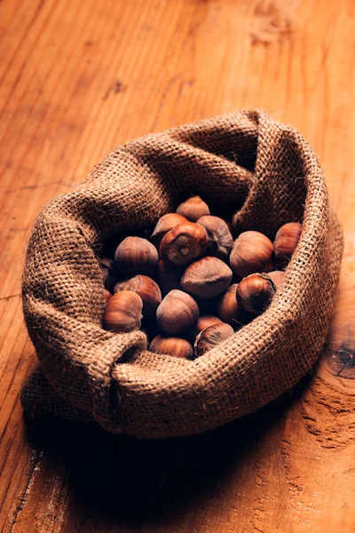 Tumpukan Hazelnut dalam karung goni di atas meja kayu — Stok Foto
