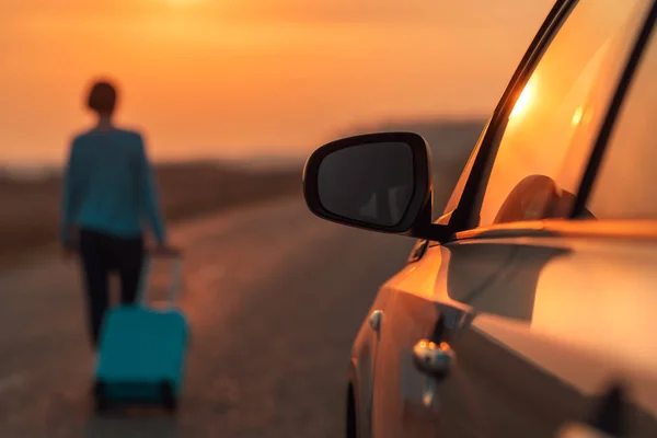Vrouw met reiskoffer loopt weg van de auto — Stockfoto