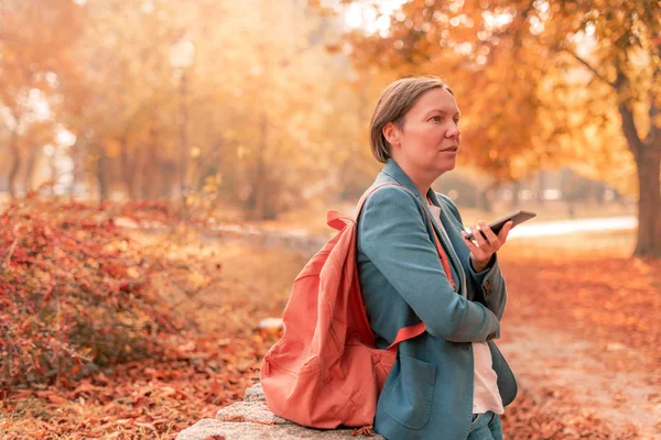 İş kadını sonbahar parkında cep telefonuyla konuşuyor. — Stok fotoğraf