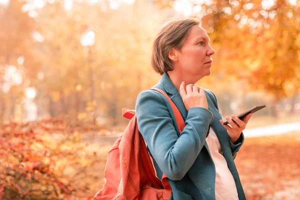 Podnikatelka mluví na mobilním telefonu v podzimním parku — Stock fotografie