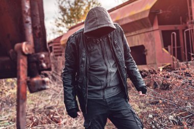 Yüzü olmayan evsiz bir adam, eski moda yük treninin arasında.