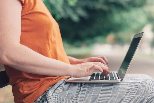 Mulher usando computador portátil no banco de parque — Fotografia de Stock