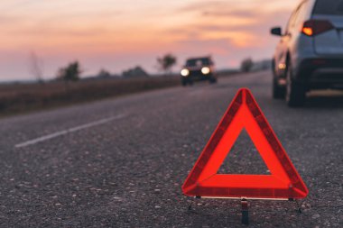 Gün batımında yol üzerinde uyarı üçgeni işareti