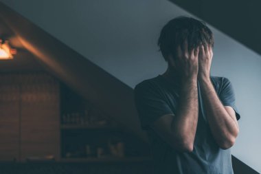 Depresyondaki adam mutfak penceresinin yanında ağlıyor.