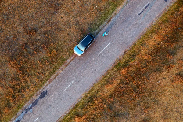 Kobieta i samochód na drodze przez trawiaste pustkowia, widok z powietrza — Zdjęcie stockowe