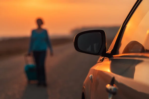 Vrouw met reiskoffer loopt weg van de auto — Stockfoto