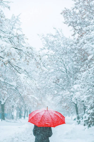 妇女在红色伞下走在冬天雪 — 图库照片