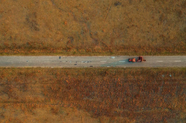 Antiguo tractor en camino de asfalto desgastado a través de prado de campo herboso —  Fotos de Stock