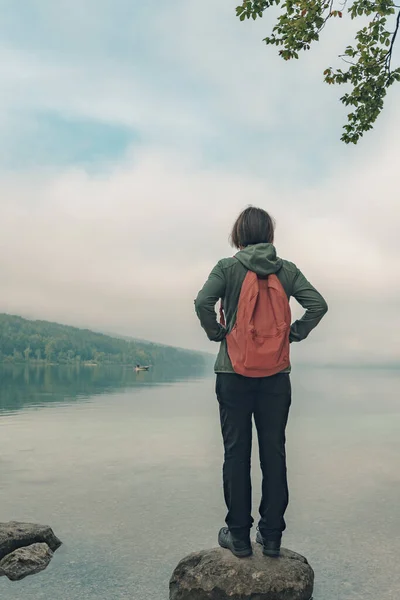 Жіночий пішохід стоїть на скелі і дивиться на озеро — стокове фото