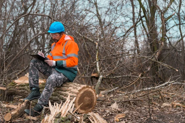 Técnico forestal escribiendo notas en papel de bloc de notas del portapapeles en — Foto de Stock