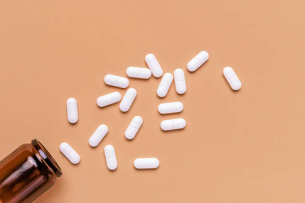 Film coated white oval pills spilled from bottle, top view — Stock Photo, Image