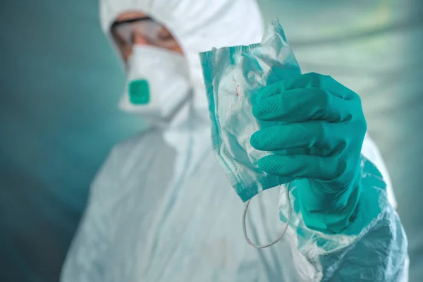 Epidemiologist memegang masker pernapasan dengan noda darah — Stok Foto