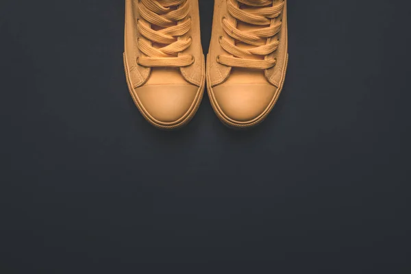Modern yellow canvas sneakers on dark background, top view — Stockfoto