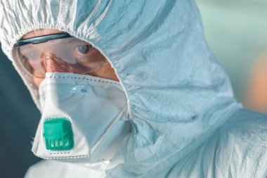 Endişeli epidemiyoloji uzmanı, koruyucu giysiler içindeki epidemiyolojistin portre fotoğrafını yakından çek.