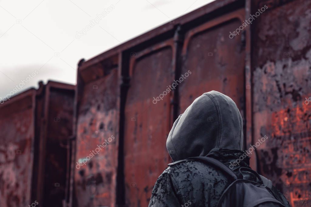 Homeless immigrant walking by freight train wagons, conceptual image with selective focus