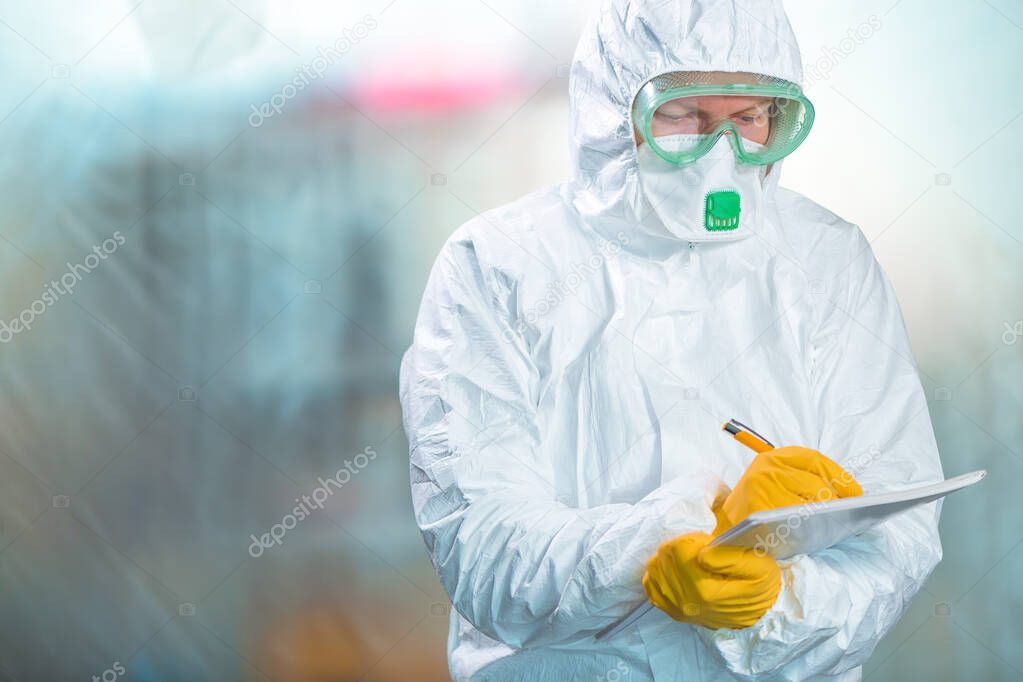 Female epidemiologist in protective clothing writing research report in virus quarantine, medical professional working