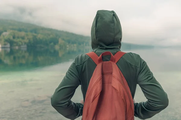 Rear view of female hiker enjoying the view of lake in misty summer morning