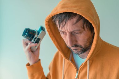 Sarı kapüşonlu kapüşonlu fotoğrafçı elinde klasik SLR kamera, seçici odaklı.