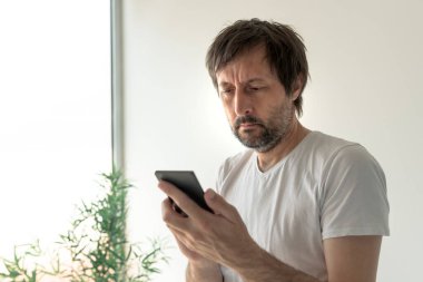 Sabahın erken saatlerinde cep telefonundan mesaj alan adam.