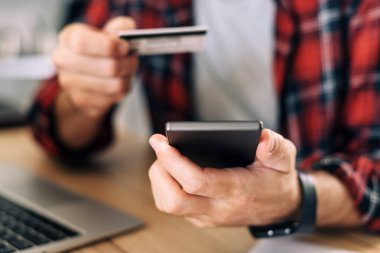 Akıllı telefon ve kredi kartı kullanarak internet üzerinden alışveriş yapmak, e-ticaret konseptinde erkeklerin ellerini kapatmak.