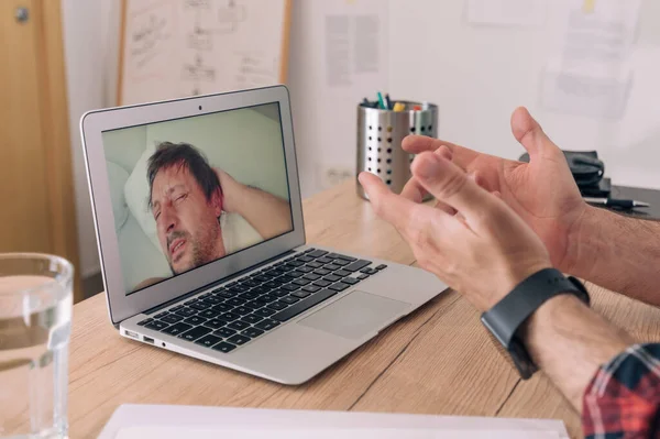 Business video call during self-isolation quarantine, manager talking over internet connection to a sleepy employee, selective focus