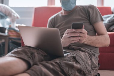 Evden çalışmak - covid-19 Coronavirus salgını sırasında telekomünikasyon, dizüstü bilgisayar ve cep telefonu kullanan adam
