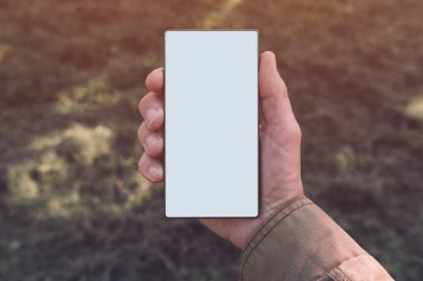 Akıllı telefon ekran modeli, modern cep telefonu cihazını tutan adam doğada beyaz beyaz ekranlı.