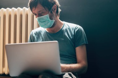 Virüs salgını sırasında evdeki karantinada dizüstü bilgisayar kullanan bir adam.