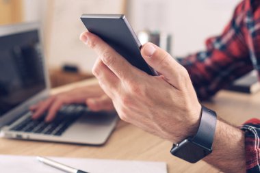 Ofiste akıllı telefon ve dizüstü bilgisayar kullanmak, modern elektronik aletleri kullanarak erkeğin ellerini kapatmak, telekomünikasyon, seçici odaklanma