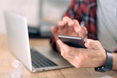 Ofiste akıllı telefon ve dizüstü bilgisayar kullanmak, modern elektronik aletleri kullanarak erkeğin ellerini kapatmak, telekomünikasyon, seçici odaklanma