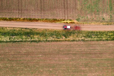 Toprak yolda tarımsal traktörün havadan görünüşü tarımsal tarlalarda sürüş, insansız hava aracı pov