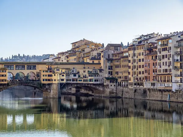 Florencie v Itálii v zimním slunci. Řeka Arno a část slavného Ponte Vechio, Starý most, s neidentifikovatelnými turisty, v lednu 2020. Stock Obrázky