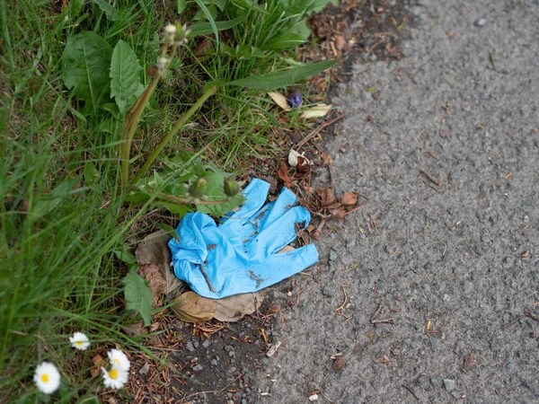 Disposable blue PPE glove abandoned by roadside, COVID19, coronavirus risk. Hand protection, Personal Preventive Equipment. — Stock Photo, Image