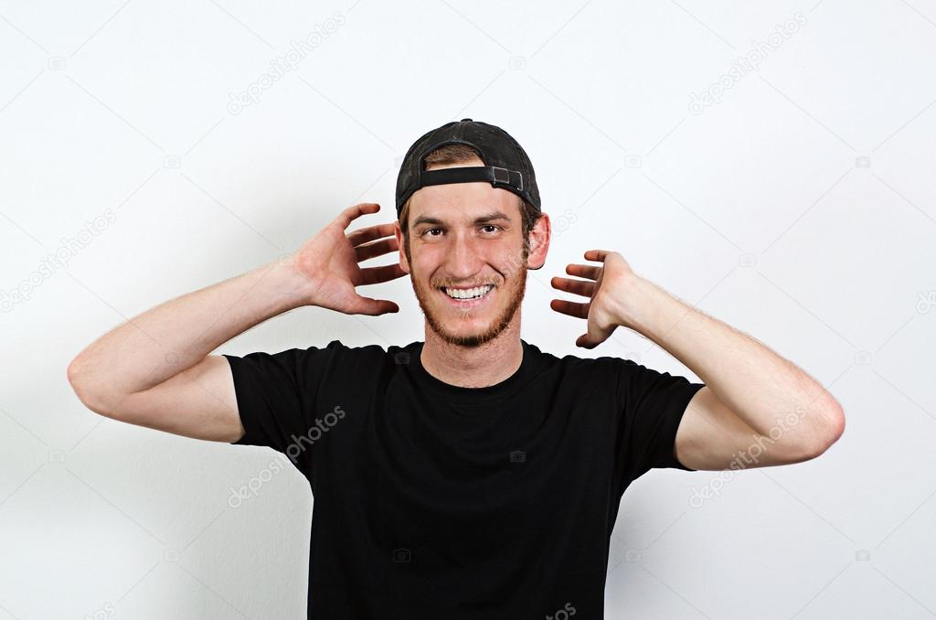 Joyful and Smiling Happy Young Adult Male in Dark T-Shirt and Baseball Hat Worn Backwards