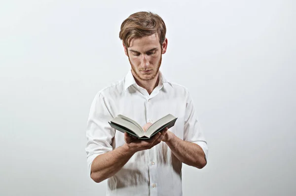 읽기 그의 손에 책을 보유 하 고 서 흰 셔츠에 젊은 성인 남자 — 스톡 사진