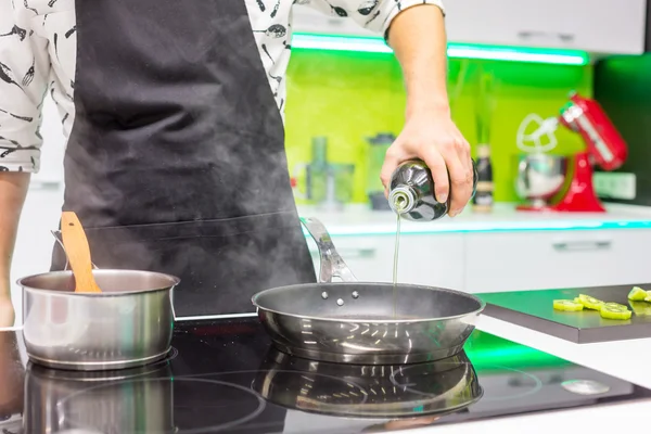 Man's hand pouring oil in pan — Stock Photo, Image