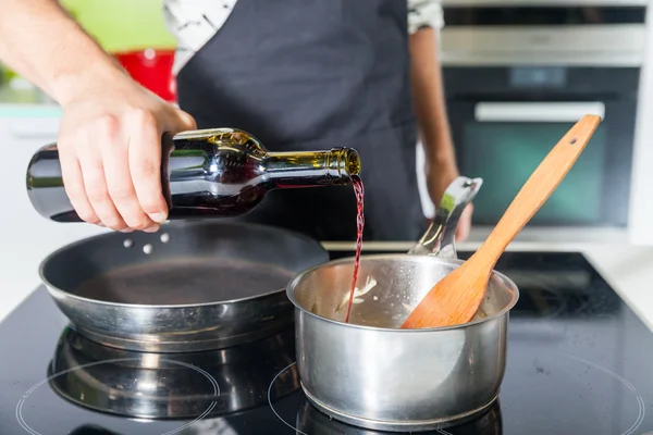 Man 's hand louring wine in pan — стоковое фото