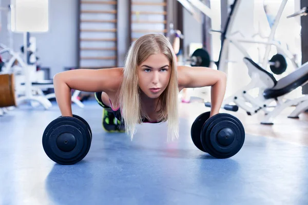 Girl doing push-ups with dumbbells — Stock Photo, Image