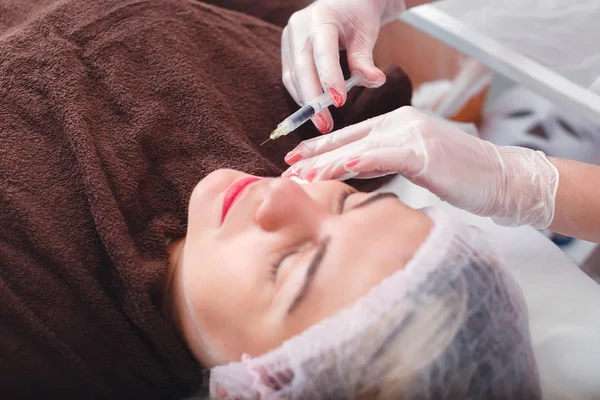 Dokter maken van injectie in gezicht van vrouw — Stockfoto